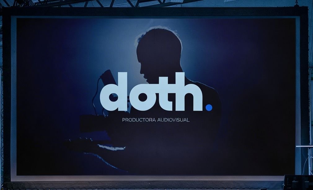 Sala oscura con una pantalla grande que proyecta el logo de DOTH