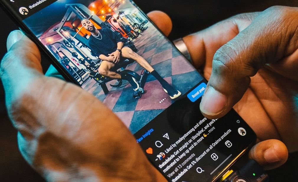 Manos sosteniendo un teléfono móvil que muestra una publicación en una red social