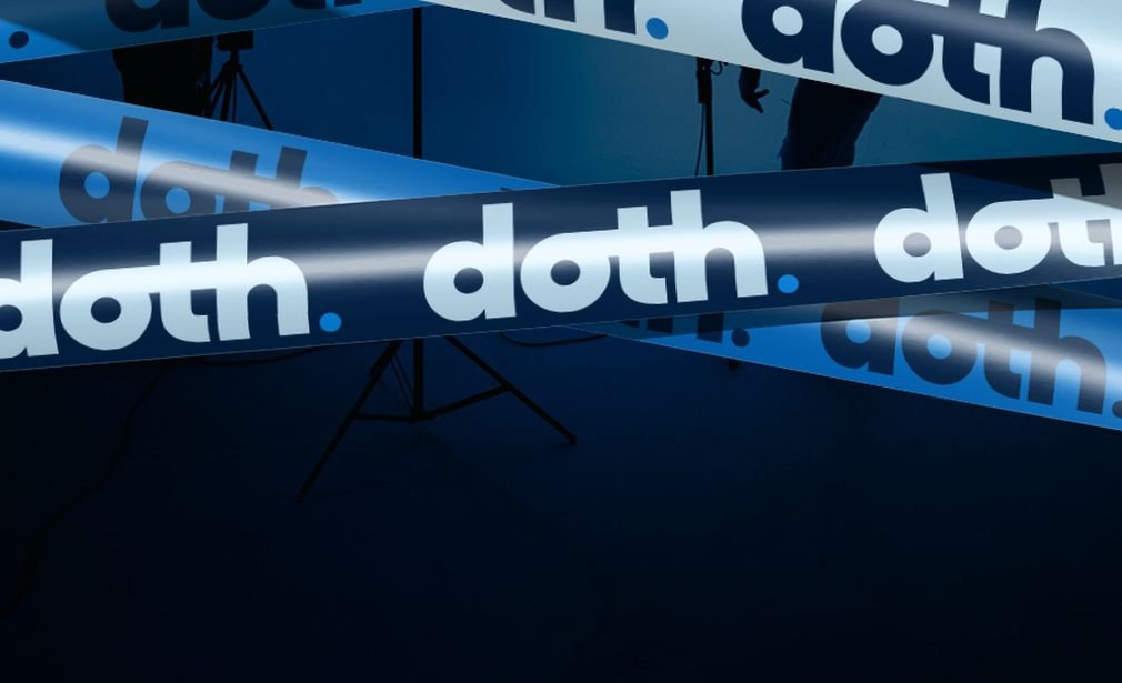 Cintas azules con el logo de DOTH sobre un plató con focos y trípodes en la penumbra