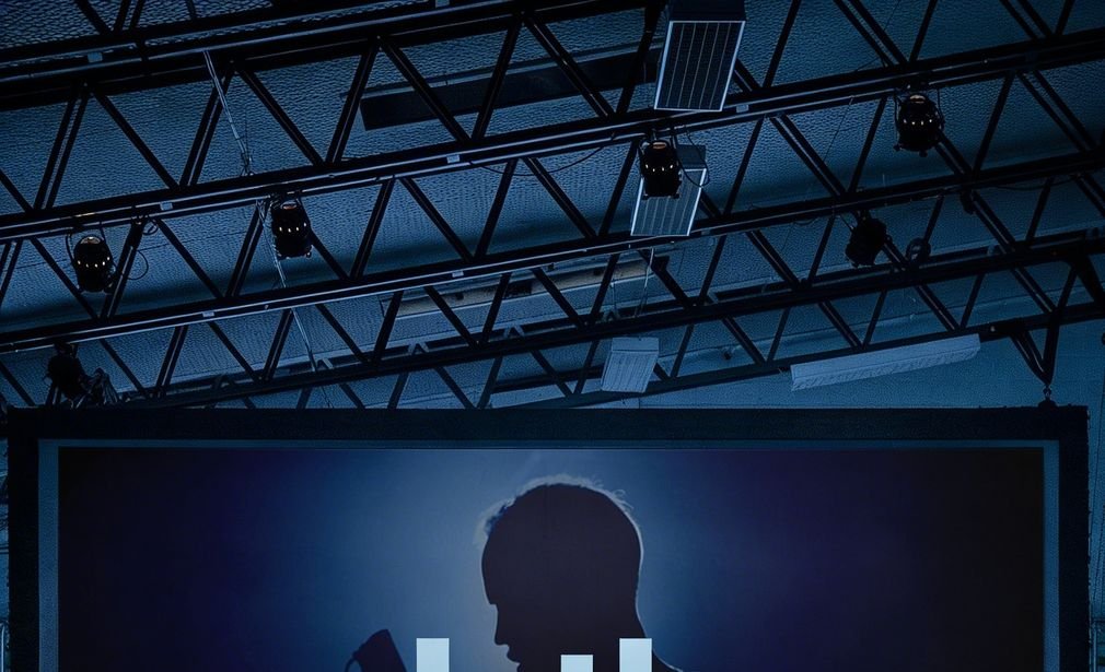 Techo de una sala con rieles de iluminación sobre una pantalla de proyección